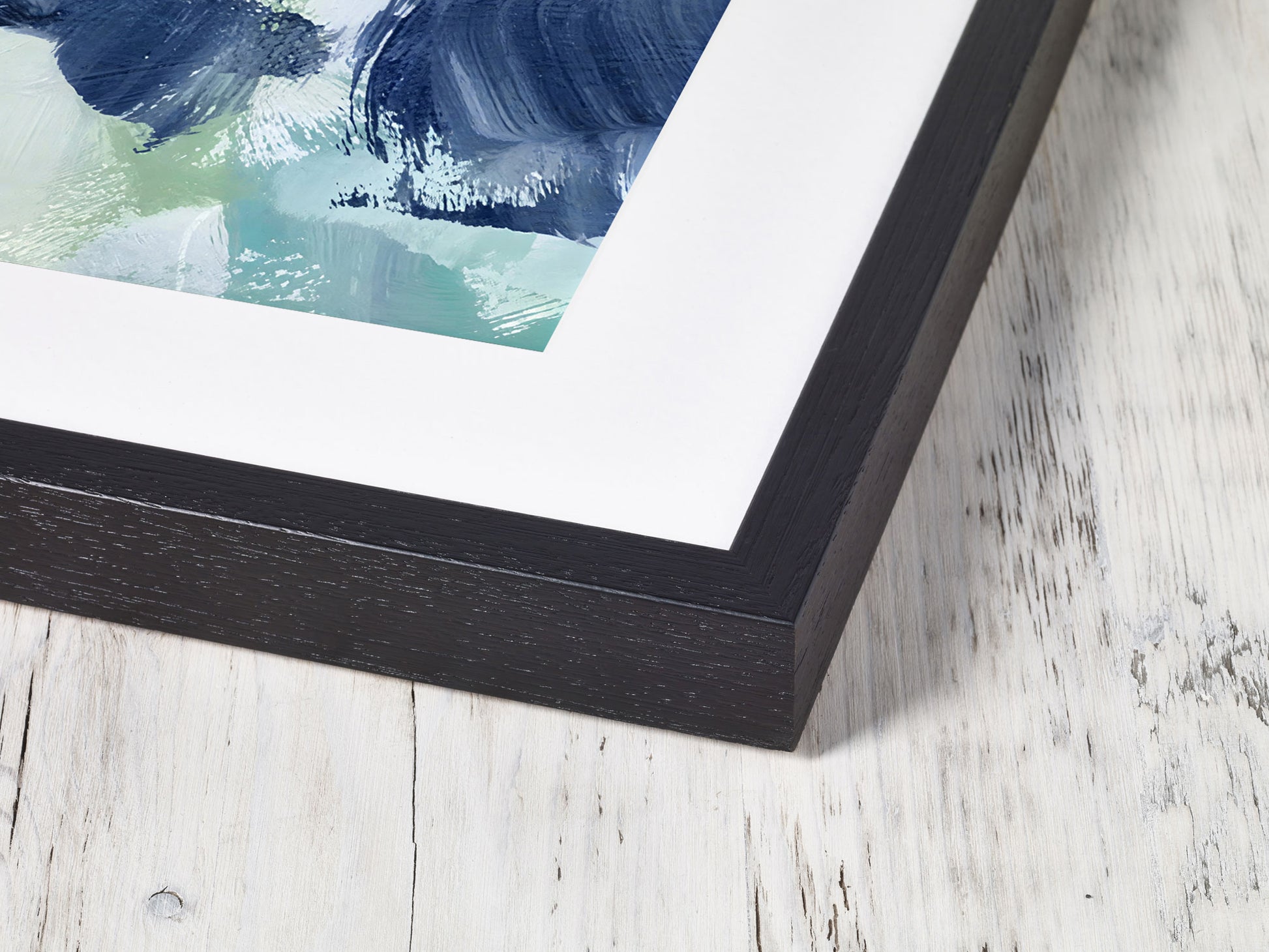 Framed abstract artwork with blue and green hues on a light wooden surface