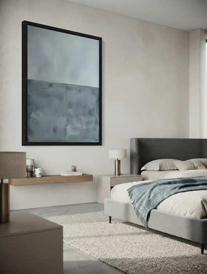 A modern bedroom featuring a Minimalist abstract painting for sale with thick blue gray texture by Noho Art Gallery with a black frame, hung above a floating wooden shelf. The room has neutral beige walls, a gray upholstered bed with a blue throw blanket, and a textured light gray rug.