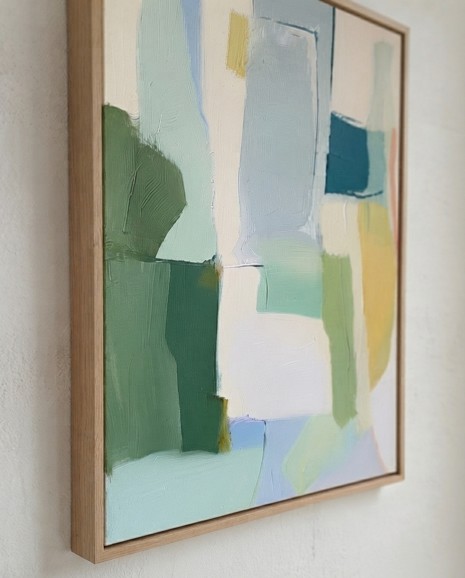 Framed Large Sage Green and Blue Minimalist Abstract Canvas Painting by Noho Art Gallery hanging on a white wall, featuring broad blocks of green, blue, white, and pale yellow paint with a light natural wood frame.