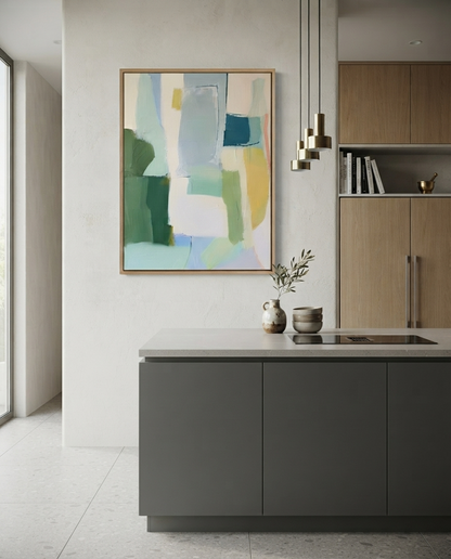 An Large Sage Green and Blue Minimalist Abstract Canvas Painting By Noho Art Galery with shades of green, blue, yellow, and white, framed in light wood and hung on a textured off-white wall above a modern kitchen island.