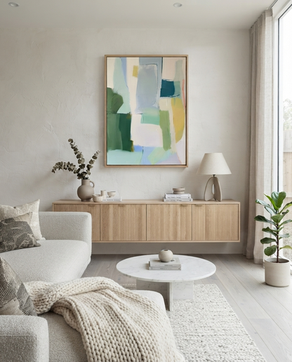 An Large Sage Green and Blue Minimalist Abstract Canvas Painting by Noho Art Gallery in a light wood frame, displayed on a beige wall above a modern wooden credenza in a bright, contemporary living room.