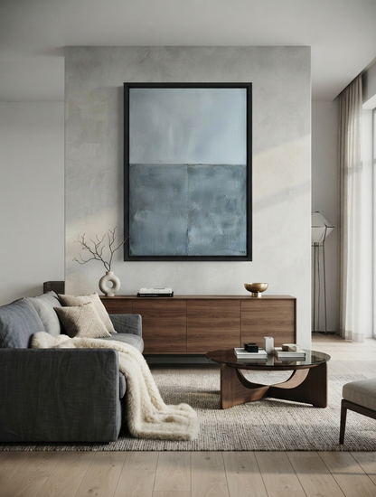 Framed minimalist blue abstract canvas art with thick texture by Noho Art Gallery on a textured light gray wall above a wooden sideboard in a modern living room setting.