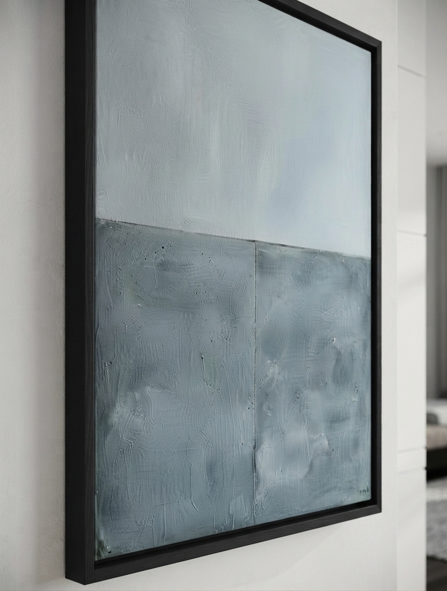 Large modern abstract art for sale with textured blue and gray acrylic finish by Noho Art Gallery with a light blue-gray upper section and a darker blue-gray lower section, enclosed in a thick black frame and mounted on a white wall.