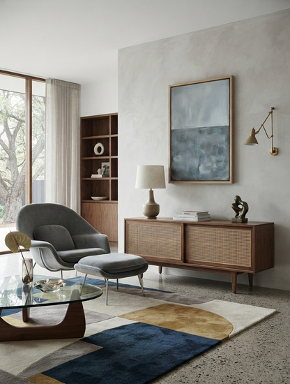 A modern mid-century styled living room featuring a gray lounge chair with an ottoman, a wooden credenza, a glass-top coffee table, and  a Large Textured Blue and Gray Abstract Canvas Art on a textured wall.