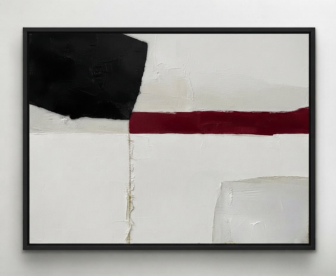 An abstract Minimalist black and white abstract canvas with red accent, modern abstract decor for office by Noho Art Gallery featuring a bold black block, a horizontal deep red stripe, and textured off-white and light gray areas, presented in a black frame against a neutral light gray wall.