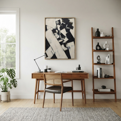 A styled home office interior featuring a mid-century modern wooden desk and matching chair in front of a large Oversized monochrome geometric abstract wall art for contemporary living spaces by Noho Art Gallery framed print on the wall. To the left is a window with a potted green plant, and to the right is a tall wooden ladder shelf holding books and decorative objects.