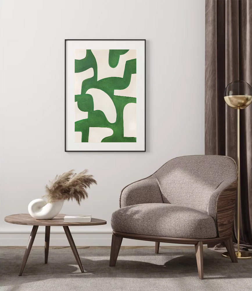 Modern living room with a gray armchair, round wooden table, and abstract green artwork on the wall.