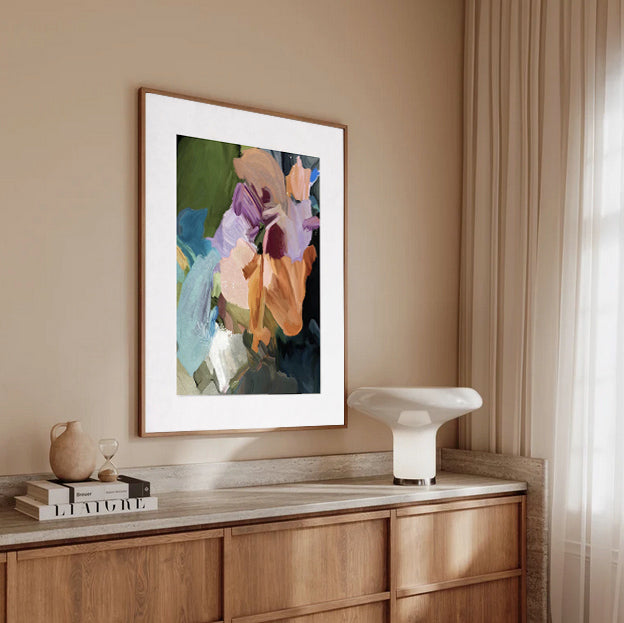 Framed abstract art on a wall above a wooden cabinet with decor items.