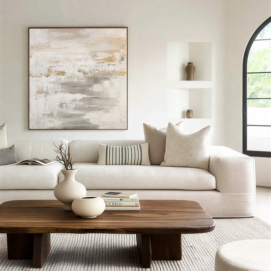 Modern living room with a white sofa, wooden coffee table, and abstract art on the wall.