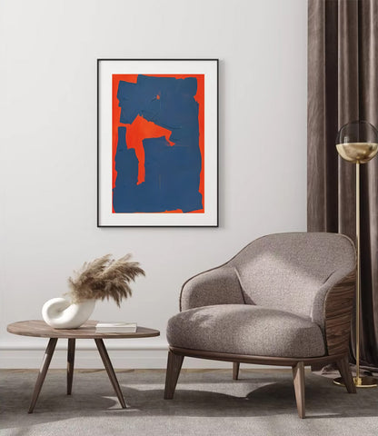 Modern living room with a gray armchair, round wooden table, and abstract art on the wall.