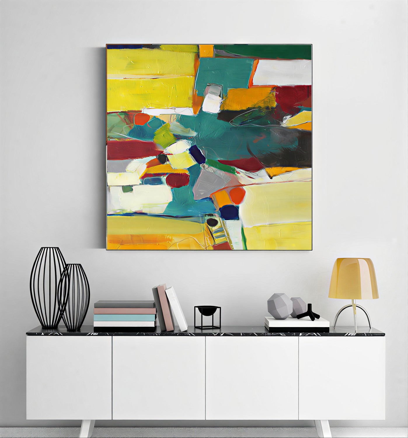 Abstract colorful painting on a wall above a white cabinet with decorative items.