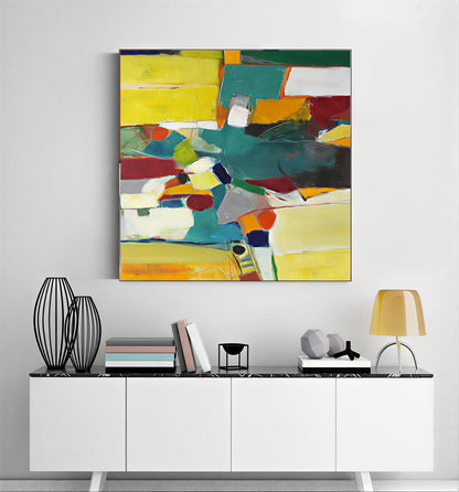 Abstract colorful painting on a wall above a white cabinet with decorative items.