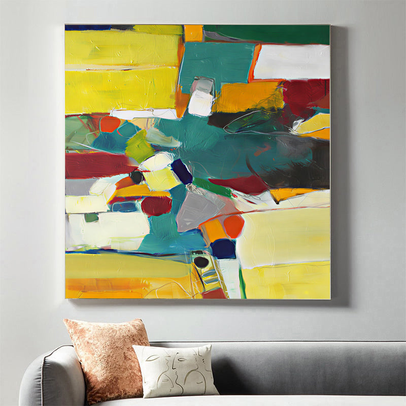 Abstract painting with colorful blocks on a wall above a sofa.